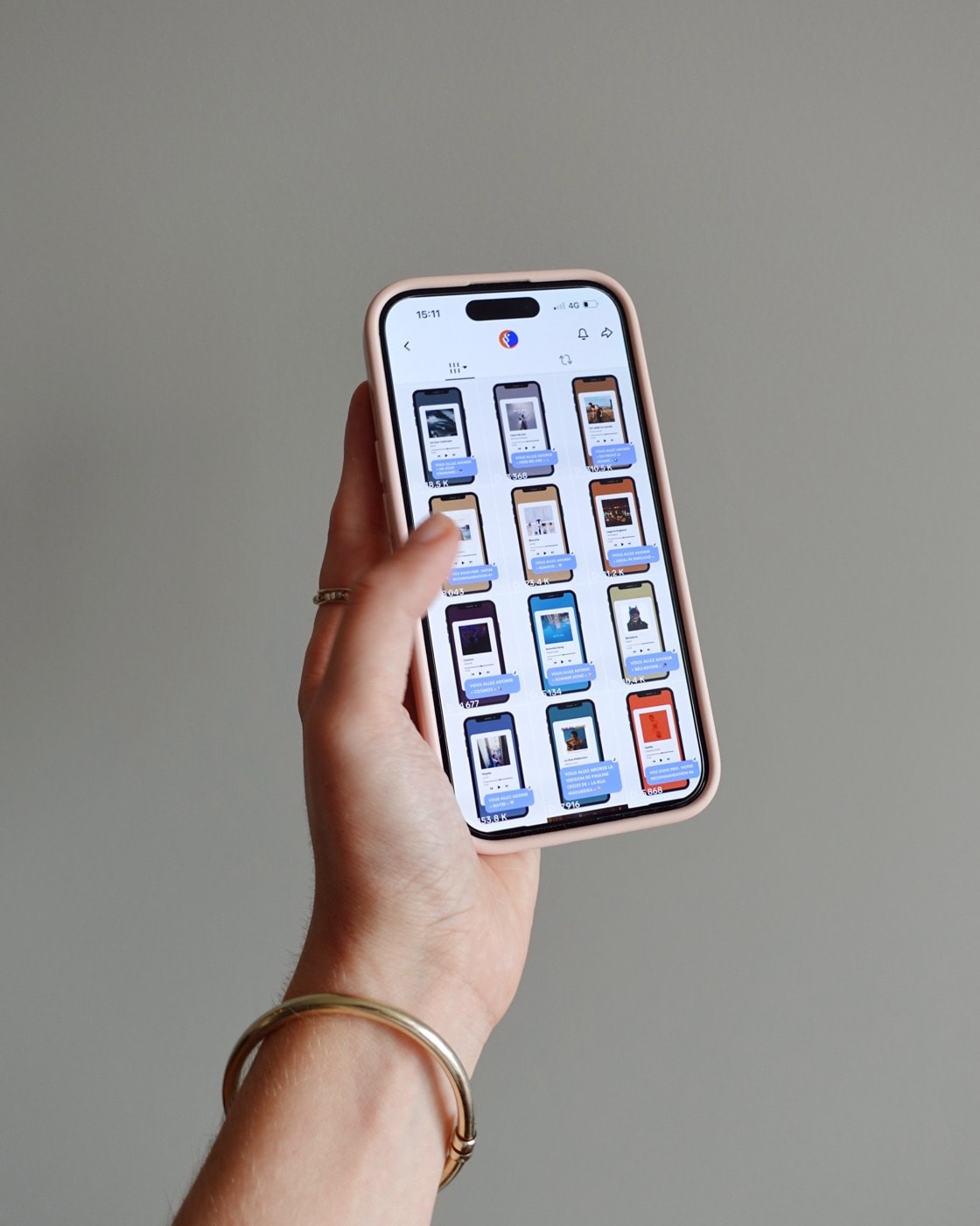 Une main tient un téléphone ouvert sur la grille des vidéos de recommandation d’Un Plan Simple, devant un mur gris.