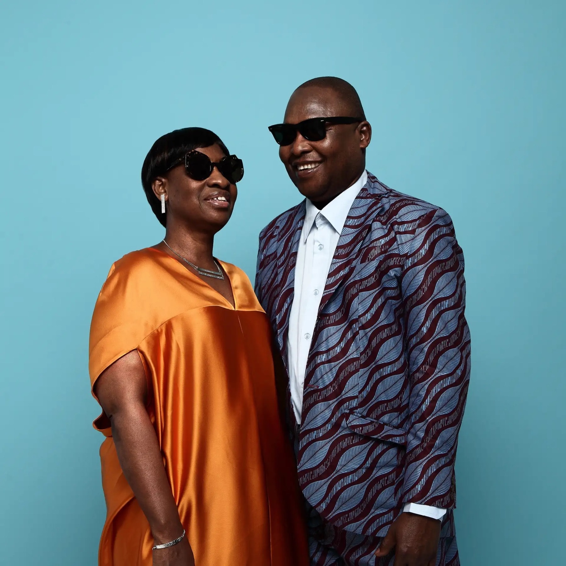 Amadou et Mariam côte à côte, lunettes noires, sur fond bleu.
