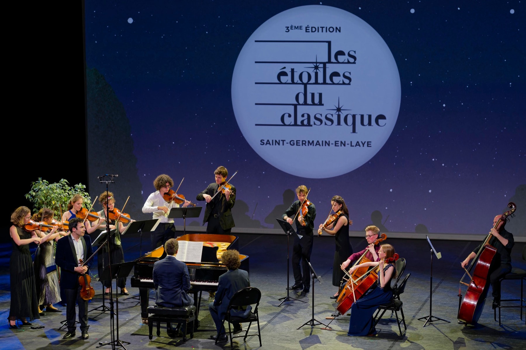 Les musiciens du festival Les Étoiles du Classique en concert, le logo projeté sur un ciel étoilé derrière eux.