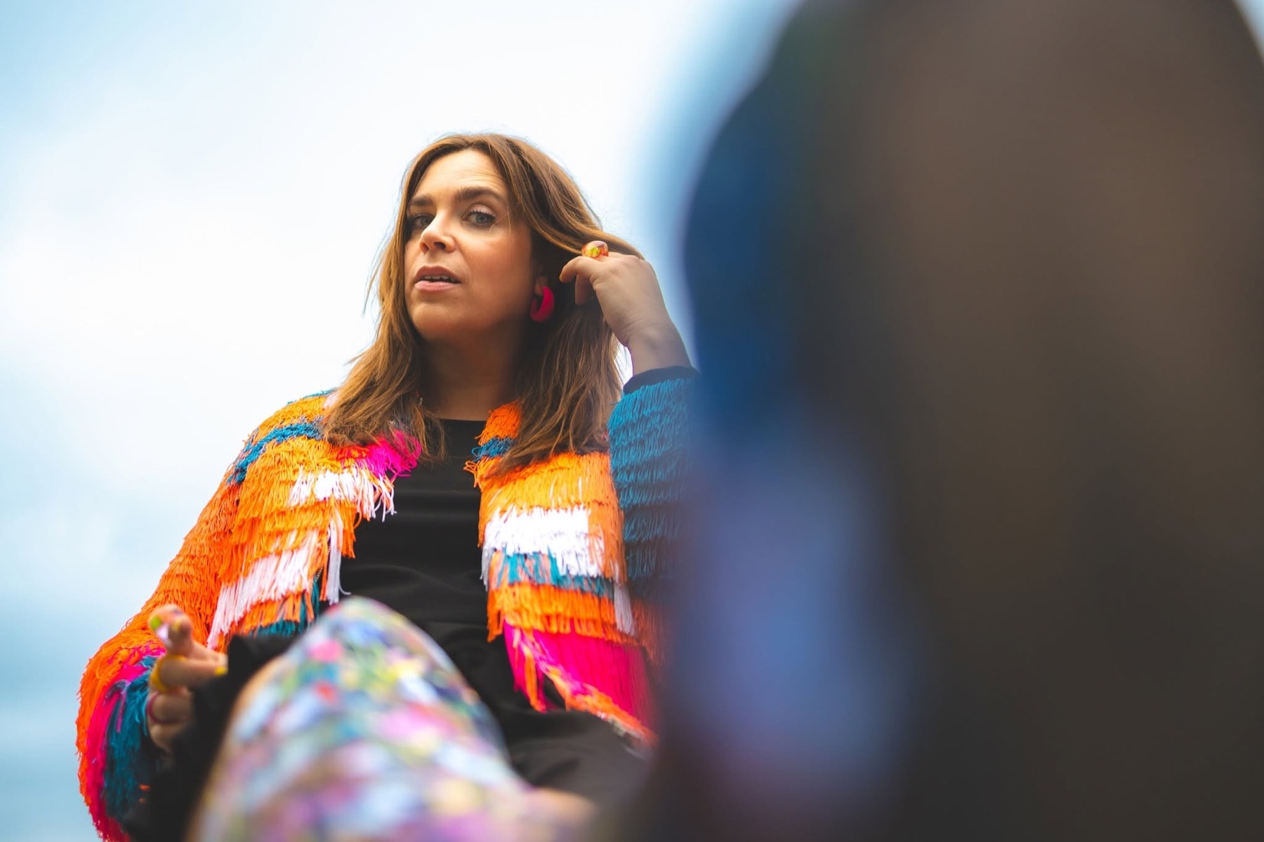Marjolaine Morasse en veste à franges colorées, en extérieur.
